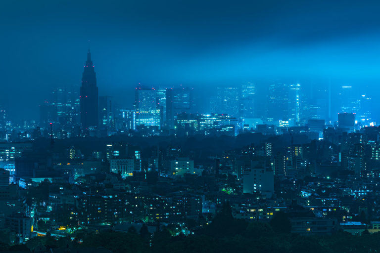 Moonlight gleaming through clouds and thick fog over Shinjuku skyline in Tokyo, Japan