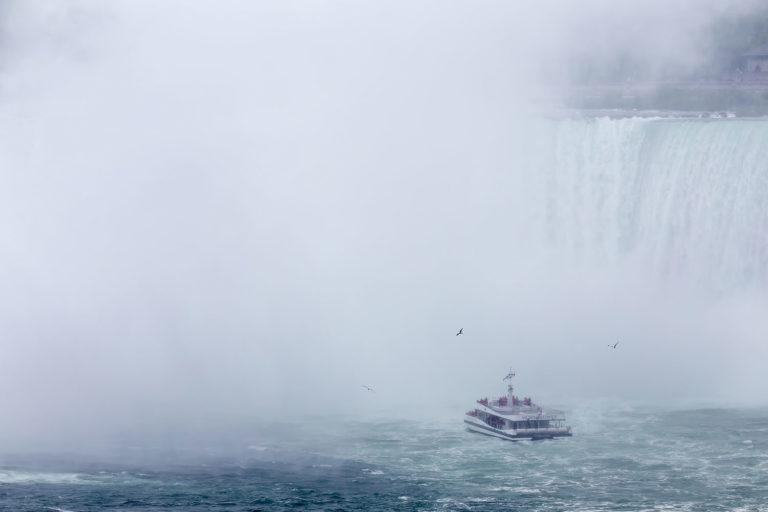 A Boat with Tourists Approaches the Mist Created by the Canadian Falls